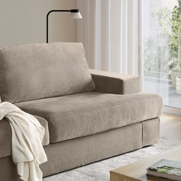 Beige SUNDBRON sofa, modern & compact, next to floor lamp in cosy living space.