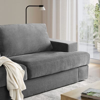 Modern grey fabric armchair, sleek design, fits in small spaces. Blanket draped, cosy for living room.