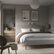 Cosy bedroom with wide-headboard bed, art, lamp, chair, and blanket - modern minimalist.