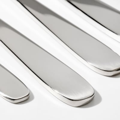 Close-up of polished stainless steel knives; sleek, reflective surfaces showcase high-quality craftsmanship.