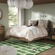 Modern bedroom with large TONSTAD bed, white linens, wood frame, hanging lamps, green chequered rug, two nightstands, large window, trees outside.