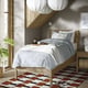 TONSTAD bed in neutral tones, wooden frame, white linens, modern design, large, with chequered rug, plants, large lamps, grey walls.