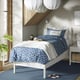 Modern bedroom with white TONSTAD bed, geometric blue linens, hanging lamps, bedside table, and plant, emphasising minimalist design.