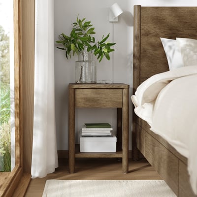 Minimalist bedroom with TONSTAD bedside table, green leaves, wooden bed, sheer curtains.