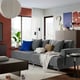 Modern living room with grey sofa, blue pillows, plant, and toys.