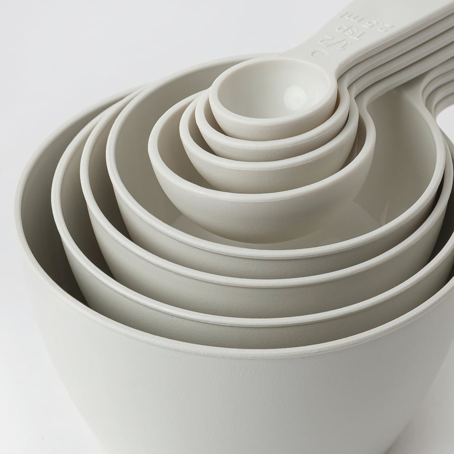 Set of measuring cups nested together, white, smooth texture, easy to stack & store.