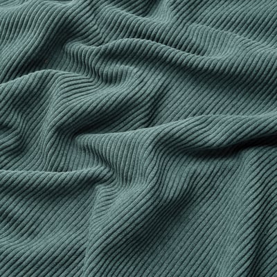Soft, wavy, green corduroy fabric close-up, showcasing its thick, comfortable texture.