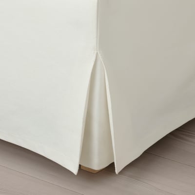 Clean, crisp white sofa with tailored pleats on wooden floor.