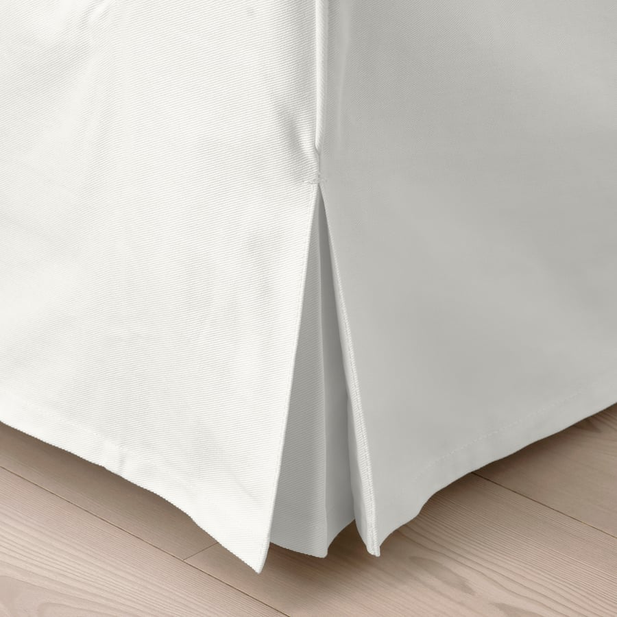 White, neatly pleated bed skirt on wooden floor, showcasing quality and design.
