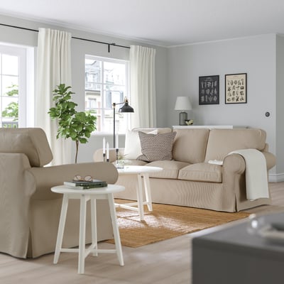 Cosy living room with beige UPPLAND sofa, coffee table, armchair, lamp, and greenery.