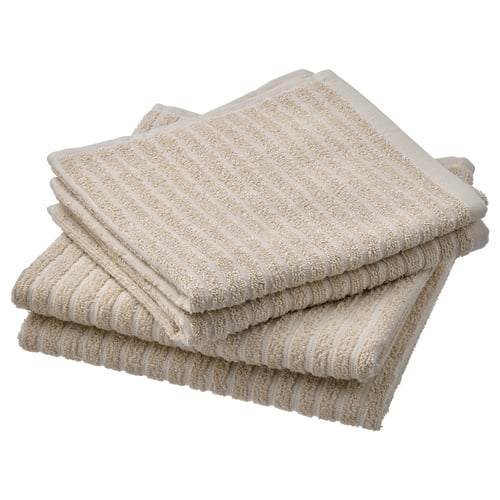 Stack of four beige bath towels, neatly folded, made of soft cotton with a ribbed texture.