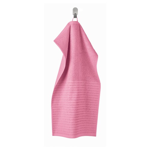 A vibrant pink VÅGSJÖN towel hangs on a hook, featuring a soft, absorbent terry texture and a ribbed weave design.