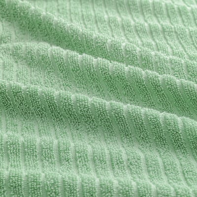 Close-up of soft, green, textured VÅGSJÖN cotton towel. Shows detailed weave, highlighting quality and absorbency.