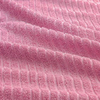 Close-up of soft, textured pink cotton towel, showcasing its absorbent quality and ribbed weave.