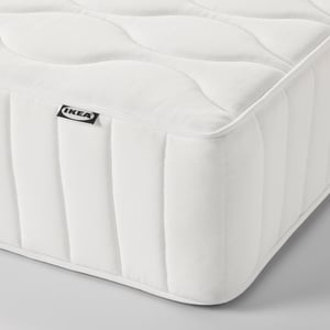 Close-up of IKEA VÅGSTRANDA mattress. Shows firm, white spring and foam mattress with reinforced edges, emphasising quality and comfort.