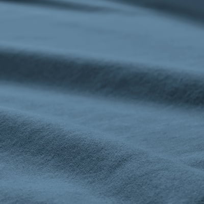 A close-up of a soft, textured jersey fabric, likely from a bed sheet, showcasing its smooth, knitted texture.