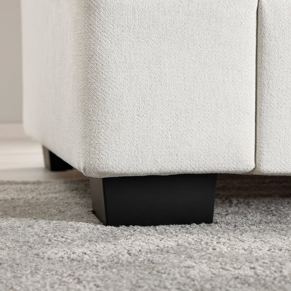 Light grey sofa close-up, showing plush cushions and dark wooden legs, highlighting comfort and quality.