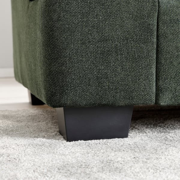 Green upholstered furniture with dark wooden legs on a light carpet.