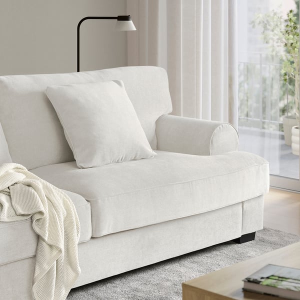 White VENNGARN sofa with cushions near window, book on side table.