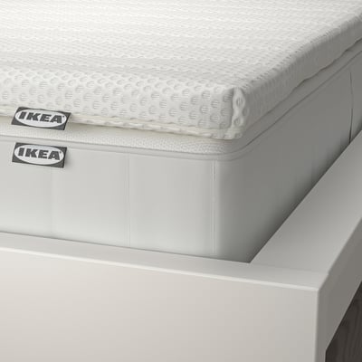 Close-up of the corner of an IKEA mattress, showcasing its layers and clean design. Labels visible indicating brand and model.