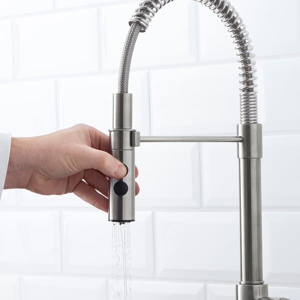 Persons hand controls water flow from modern kitchen tap. Stainless steel VIMMERN tap has dual spray function.
