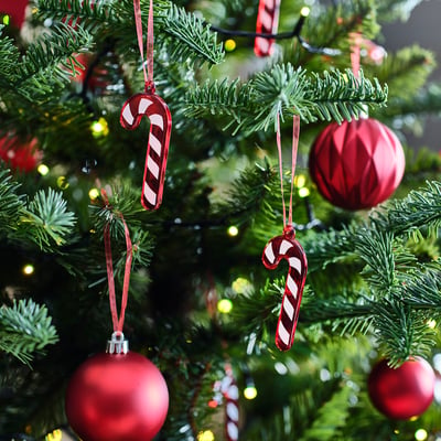 Christmas tree decorated with red glass ornaments and candy canes, lights twinkling in background.