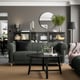 Modern living room with green VISKAFORS sofa, black coffee table, and dark shelves with decor.